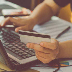 hand holding credit card at computer