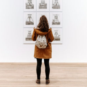 girl looking at art on white wall
