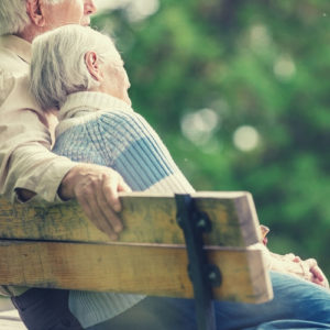 elderly couple sitting on bench outside outdoors