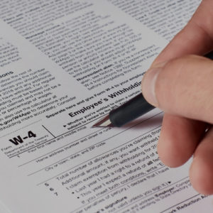 hand with pen filling out Form W-4