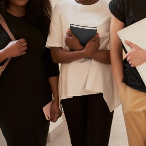 college students in hallway with backpack laptop book phone